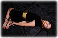 Free bondage photo Zarina barefoot, handcuffs, hogtie, leg irons, chains, cloth gag, thumbcuffs, dress, gag